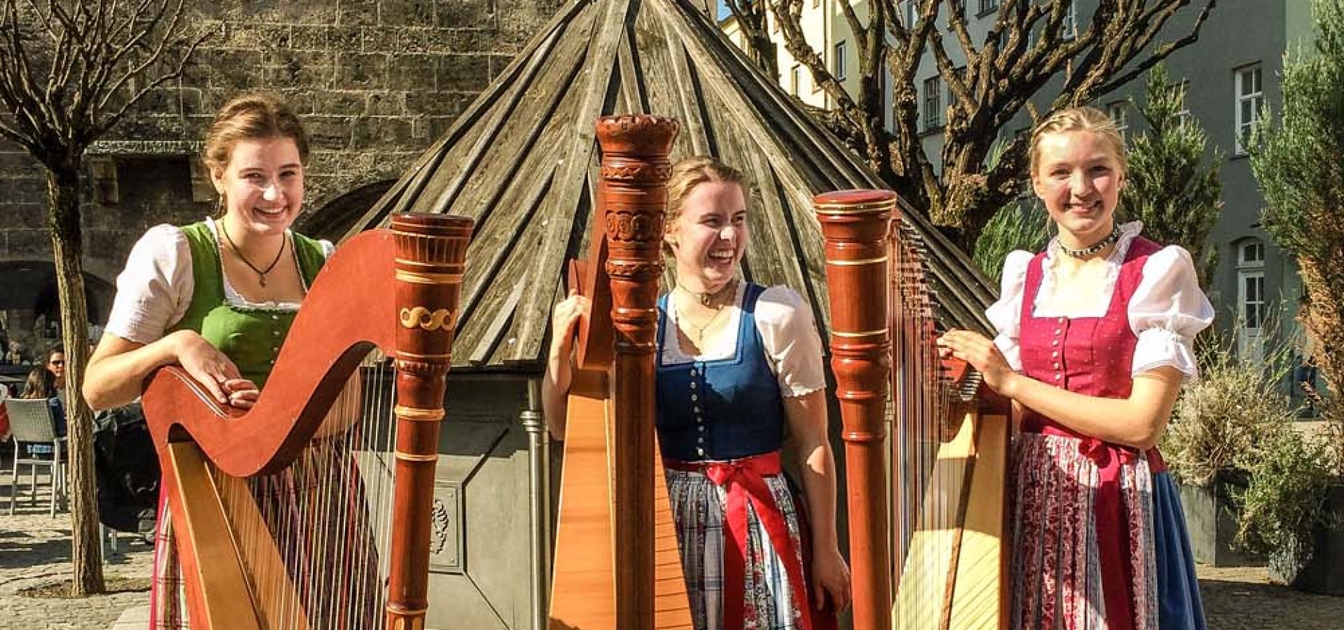 Die Seewind Harfendirndln vor dem Wasserburger Rathaus. Franziska Aberger (von links), Maria Weingartner und Magdalena Kurfer gewannen in der Sparte instrumentales Vorspiel den Wanderpokal, den 43. Wasserburger Löwen (zu ihren Füßen), in den dortigen 45. Volksmusiktagen., © Musikschule Grassau